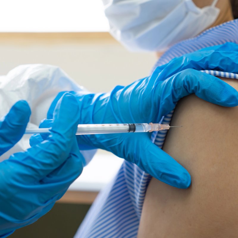 Close-up of nurse giving a vaccine with syringe and blue gloves.